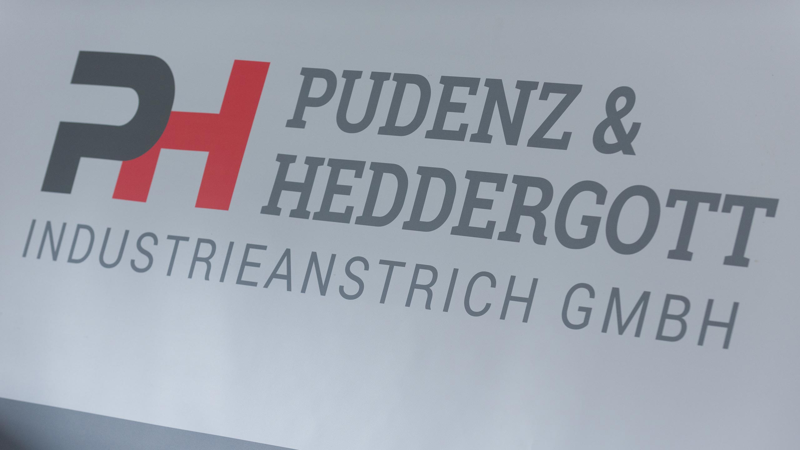 Nahaufnahme Firmenschild mit Firmenlogo an der Außenwand der Firma Pudenz und Heddergott GmbH aus Wilbich